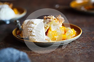 Serving of Drop Biscuit Peach Cobbler and Melting Ice Cream photo