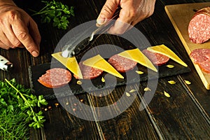 Serving food. The chef places cheese on a serving board for a sausage and parsley appetizer. Place for advertising