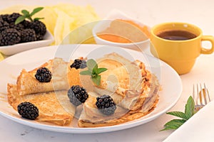 Serving French Crepes with fresh berries and honey on the plate