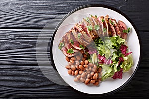 Serving grilled beef steak with fresh salad and beans close-up o