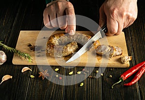 Serving a meat dish for lunch. The chef cuts homemade fried sausage on a wooden board. Cooking national meat dishes at home