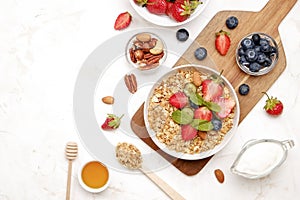 Ceramic granola bowl, assorted ingredients on table. Healthy nutritious breakfast with vegan yogurt, raw fruits, nuts and cereals.