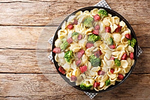 Serving of orecchiette pasta with broccoli and fried Italian sausages close-up in a plate. Horizontal top view