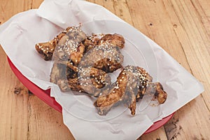 A serving of Spicy Korean Chicken wings at a restaurant. On a tray covered with greaseproof paper photo