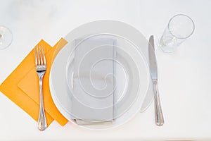 serving table. white plate, napkins, fork with knife and an empty glass on table