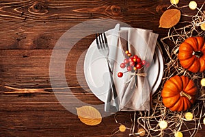 Serving for Thanksgiving dinner with plate, napkin, cutlery and pumpkins top view. Autumn table setting