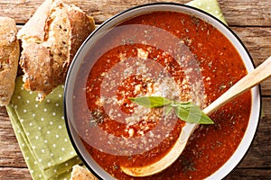 Serving of tomato-basil cream soup with cheese closeup in a bowl and bread.  Horizontal top view