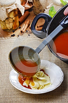 Serving tomato soup. Pouring soup into a plate