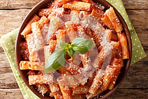 Serving of Tortiglioni pasta with parmesan basil in tomato sauce close-up in a plate. Horizontal top view