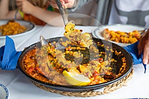 serving typical Spanish paella with mussels and clams in restaurant