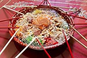 Serving of yusheng or yee sang with raw salmon belly during Chinese New Year with chop sticks laid around plate for good