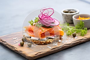 sesame bagel, lox, red onions, and capers, on a slate