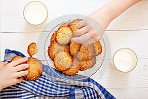 Sesame biscuits with milk for breakfast for children. Children`s hands in the frame. Children eat biscuits. View from above.