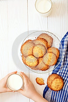 Sesame biscuits with milk for breakfast for children. Children`s hands in the frame. Children eat biscuits. View from above.