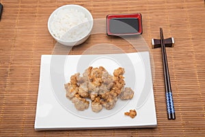 Sesame chicken dish and chopsticks on bamboo placemat photo