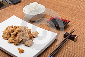 Sesame chicken dish and chopsticks on bamboo placemat photo