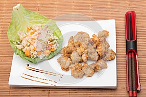 Sesame chicken dish and chopsticks on bamboo placemat photo