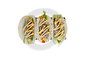 Sesame crusted ahi tuna tacos with vegetables in a soft flour tortilla on a white background