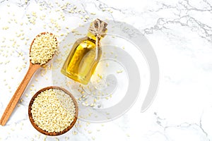sesame oil and sesame seeds on a white marble background. Healthy vegetarian food concept.