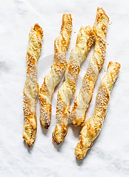 Sesame puff pastry breadsticks on a light background, top view. Delicious snack, tapas