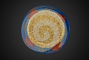 Sesame seeds in a blue glass bowl. Top view of white sesame seeds in a round bowl on a black background