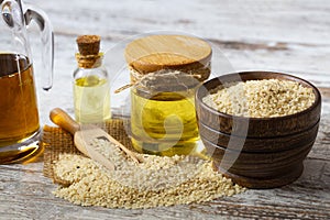 Sesame seeds in sack and bottle of oil on wooden rustic table