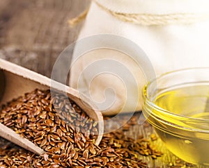 Sesame seeds in sack and bottle of oil on wooden rustic table on sunlight