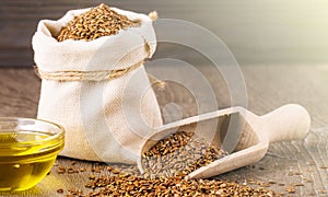 Sesame seeds in sack and bottle of oil on wooden rustic table on sunlight