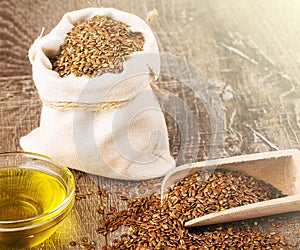 Sesame seeds in sack and bottle of oil on wooden rustic table on sunlight