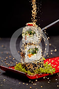 Sesame seeds sprinkling on vegetarian sushi roll tower