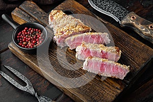 Sesame tuna steak grilled, on wooden serving board, on old dark  wooden table background