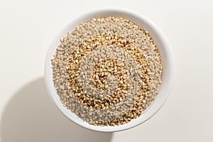 Sesamo. Top view of grains in a bowl. White background.