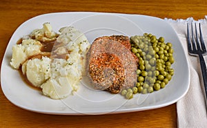 seson pork chop served with mash potatoes and peas