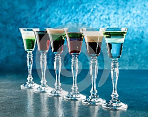 Set of alcoholic cocktails in shot glasses or shooters on dark blue background, burning cocktail. Drink and beverages