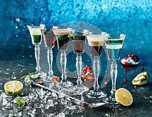 Set of alcoholic cocktails in shot glasses or shooters on dark blue background, burning cocktail. Studio shot of drink in freeze