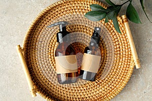 Set of amber glass bottles of natural cosmetics for personal hygiene in rattan tray. SPA organic beauty products top view