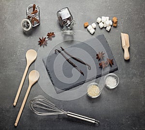 Set of aromatic spices, sesame seeds, salt, sugar and kitchenware, on gray