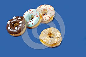 Set of assorted donuts with blue glaze, sprinkle, almond crumbs, chocolate and marshmallows close-up isolated on a purple