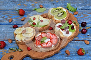 Set of assorted healthy wholewheat bread sandwiches with fruit, cheese and leafy green herbs on picnic wooden table