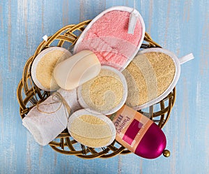 A set of bath sponges from a loofah with soap, a towel and shampoo in a basket