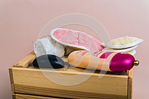 A set of bath sponges from a loofah with soap, a towel and shampoo on a wooden box