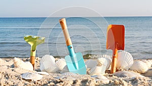 Set of beach toys for kids on a white sand beach, in the background of sea or ocean. Summer vacation banner concept.
