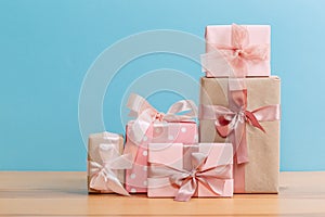 Set of beautiful different gift boxes made by handmade with pink bows on a wooden table with a blue background. flat lay