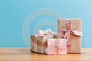 Set of beautiful different gift boxes made by handmade with pink bows on a wooden table with a blue background. flat lay