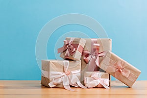 Set of beautiful different gift boxes made by handmade with pink bows on a wooden table with a blue background. flat lay