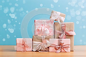 Set of beautiful different gift boxes made by handmade with pink bows on a wooden table with a blue background. flat lay