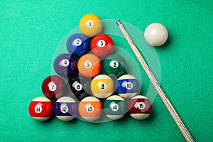 Set of billiard balls and cue on green table, flat lay