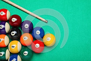 Set of billiard balls and cue on green table, flat lay. Space for text