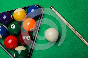 Set of billiard balls with rack and cue on green table, flat lay