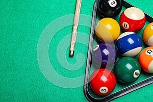 Set of billiard balls with rack and cue on green table, flat lay. Space for text